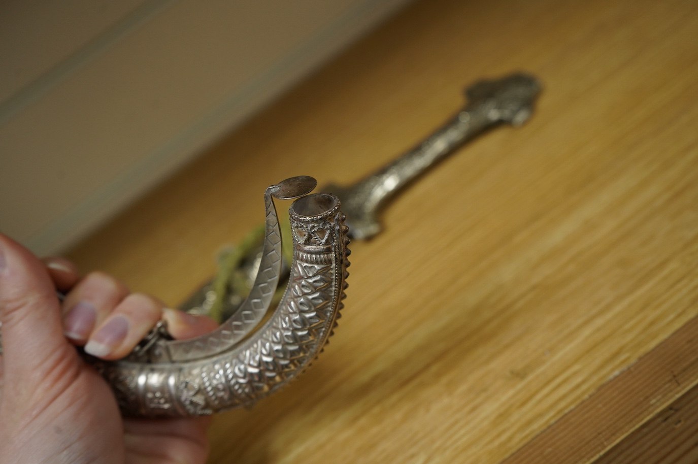 An Omani silver spice box in the form of a curved powder flask, together with a Moroccan dagger Jambiya with nickel hilt and sheath, both 20th century. Condition - fair.